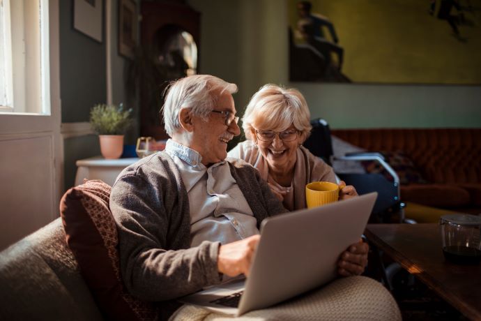 Een foto van een ouder koppel dat glimlachend naar een laptop kijken